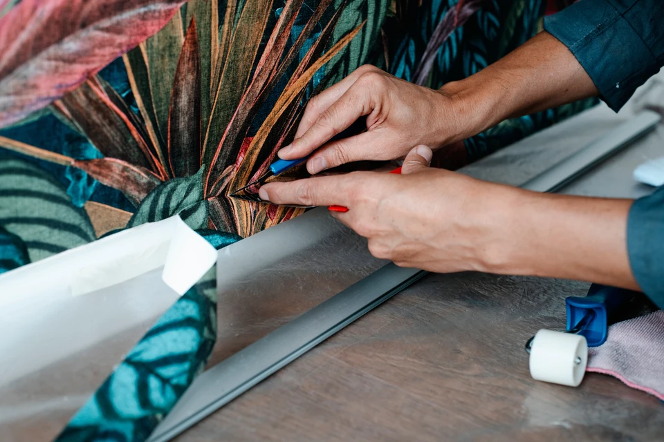 Une main applique un produit de finition transparent sur un parquet en bois naturel à l'aide d'un pinceau plat professionnel
